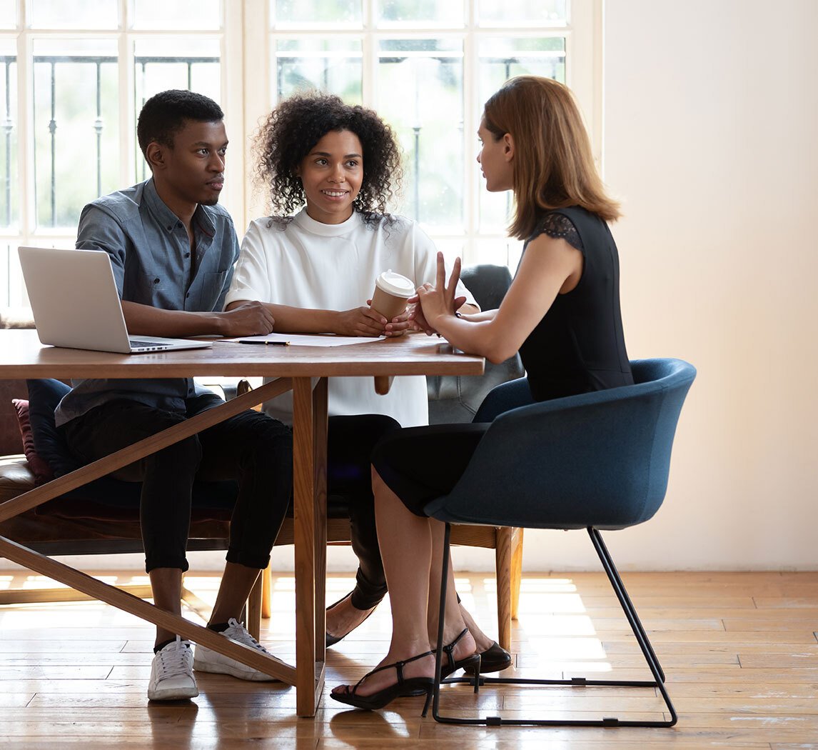 Three professionals collaborating around a table in a bright office space