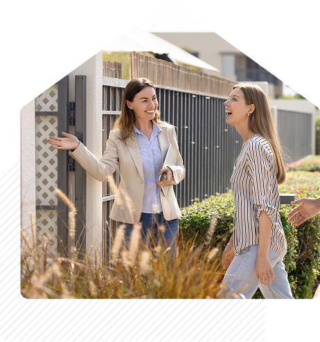 Why Real Estate Pros Choose 2-10 | Real estate agent smiling and greeting clients outside a modern home during a property showing.