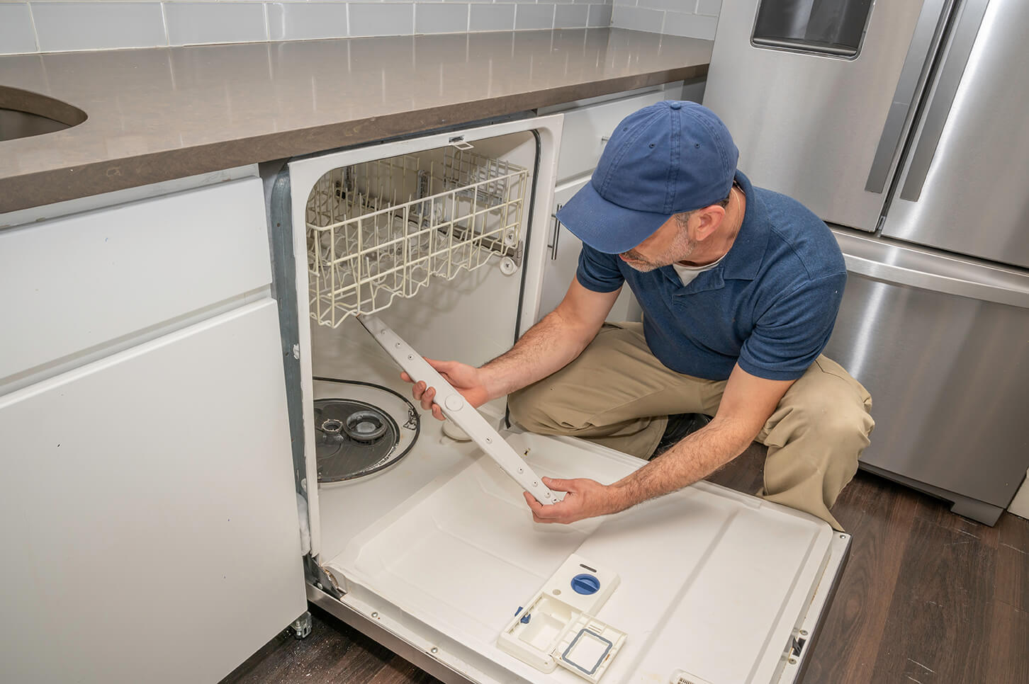Technicin performing maintenance on a dishwasher