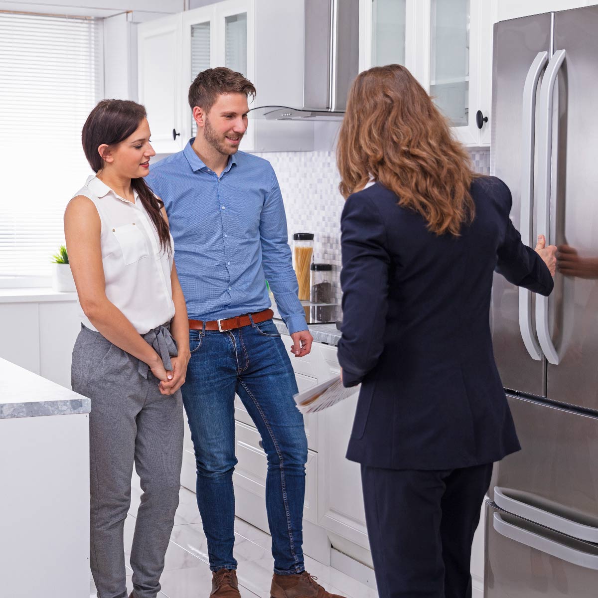 Real estate agent explaining updated appliances to couple