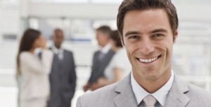 Portrait of happy young businessman with colleagues in the background