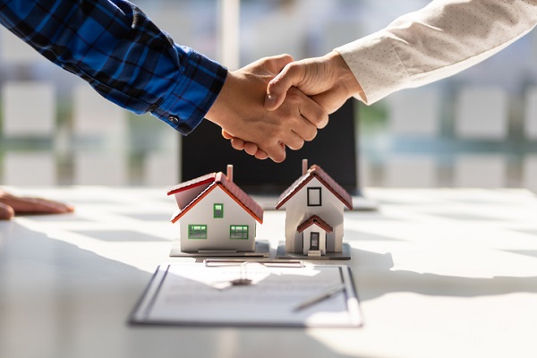 Real estate agent and home builder shake hands after the signing of the contract agreement is complete.