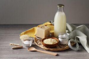 Traditional hard soap bar from Marseille (France), pure soap flakes, baking soda, cotton towel, spoon, clothes peg and home made washing up liquid in the glass bottle on the grey table.