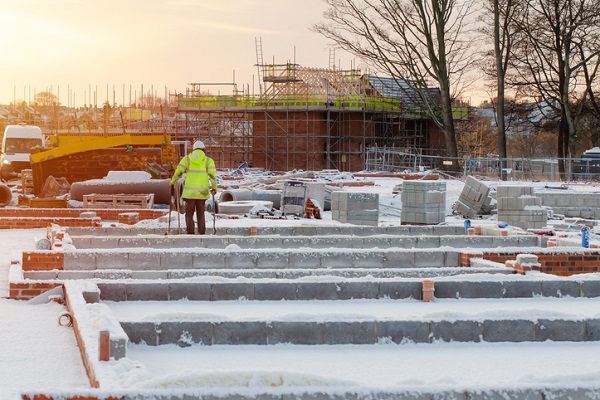 Construction worker on housing site in wintertime during construction of a new residential house. winter home building