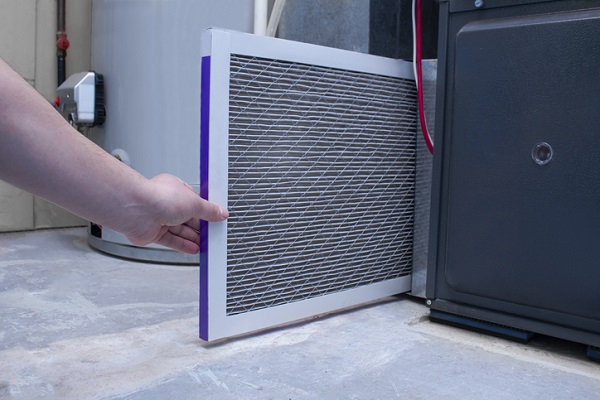 A person changing a furnace filter on a high efficiency furnace