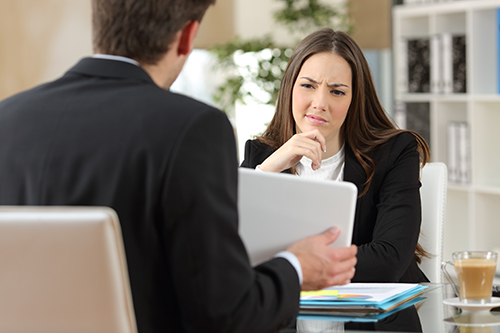 A woman looking perplexed, as though she's being confused by a scam cash buyer.