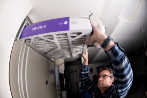 Handyman replaces the filter in the hot air furnace at a home