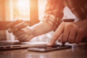 Man's hands pointing smartphone and using credit card 