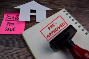 House For Sale written on a book and Red Handle Rubber Stamper Pre-Approved text isolated on the table.