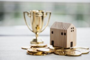 Golden trophy winner with house model and money coins. Concept of leadership property real estate mortgage in business management profit target in life. Best success prize of business as competition