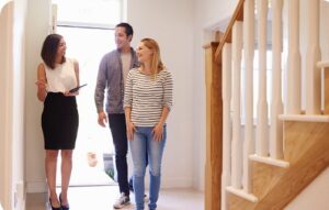 A couple and a female real estate agent smiling inside a home.