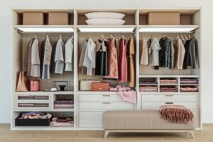 A wooden cabinet in three sections, and each section has different kinds of clothes, such as formalwear, dresses, and blazers