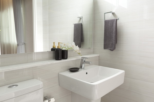 White bathroom with a square white sink, a mirror, and a dark gray towel hanging on the right side.