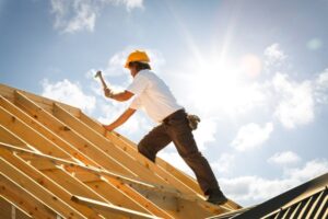 carpenter on roof trusses backlit with sunflare