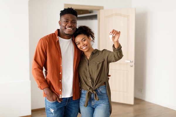 A Black man and Black woman Showing House Key Standing Among Moving Boxes Indoor