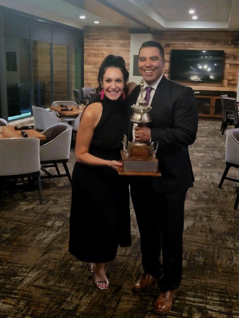 A man an woman in formal attire holding an award trophy