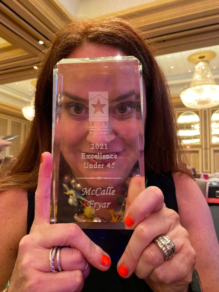 A woman with red hair holding her face up to a clear award statue.