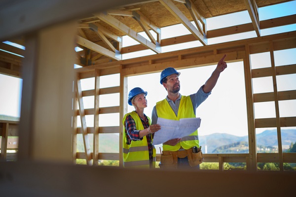 Construction engineers or architects with blueprints visiting and checking a building site of wood frame house, like the ones 2-10 HBW may protect