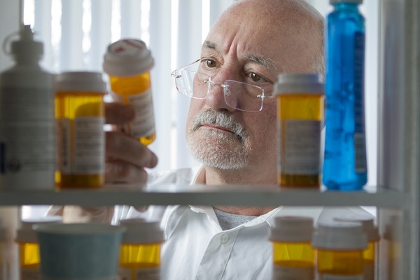 Senior man looking at prescription drugs in a medicine cabinet